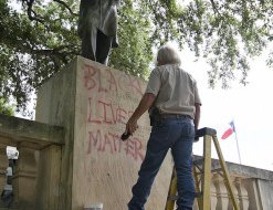Bill Tanner with UT Facilities Services works to remove graffiti from a statue of Jefferson Davis on the south mall at the University of Texas campus in Austin, Texas, on Tuesday, June 23, 2015. (Deborah Cannon/Austin American-Statesman via AP)